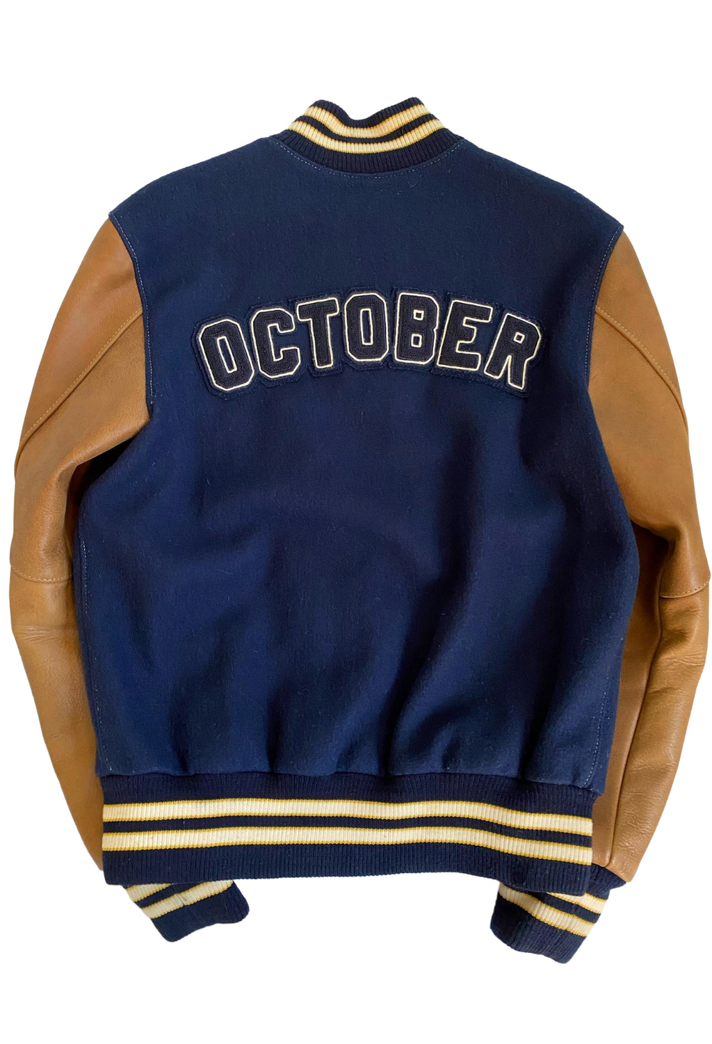 Navy varsity jacket with brown sleeves and 'OCTOBER' text on the back, on a white background. OVO X Roots Leather Wool Varsity Jacket 2015 Navy Brown