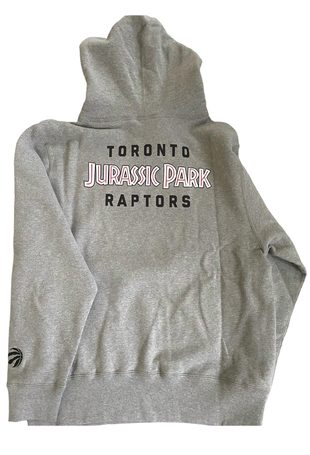 Gray hoodie with 'Toronto Jurassic Park Raptors' text on the back, displayed flat. OVO x Jurassic Park x Raptors OG Owl Hoodie 2021